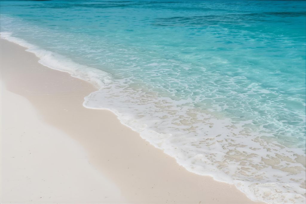  Uma fotografia de uma praia paradisíaca com areia branca e águas cristalinas, com ondas suaves quebrando na costa. A imagem evoca tranquilidade e vastidão.